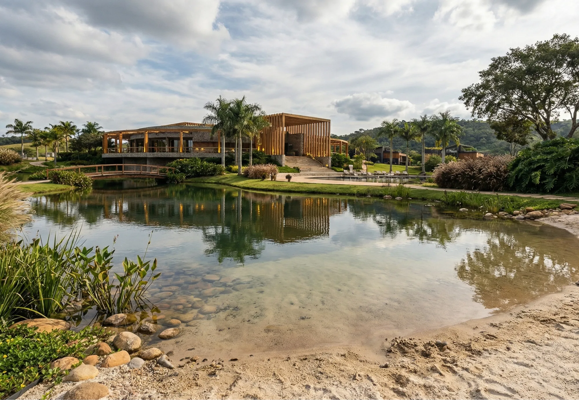 Sede reflejada en el espejo de agua del lago, con piedras y una pequeña playa en primer plano, proyecto Arsenic Arquitetos