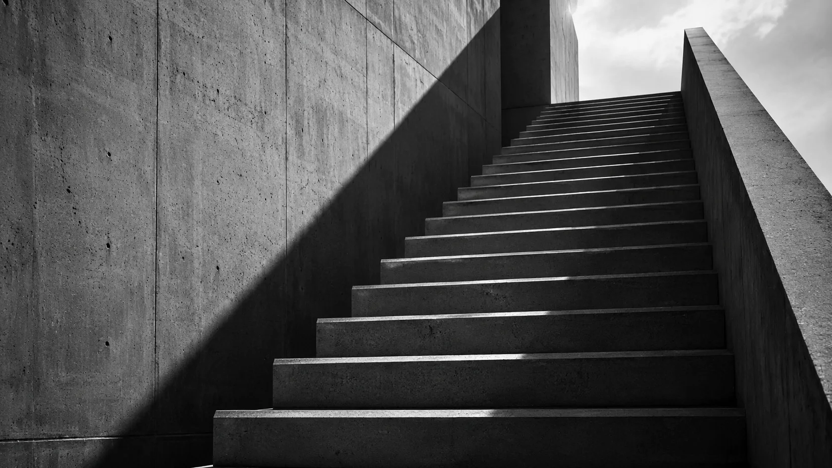 Escadaria de concreto aparente subindo em degraus sob luz dura, imagem da escada de instrumentos que cobra a função social do imóvel