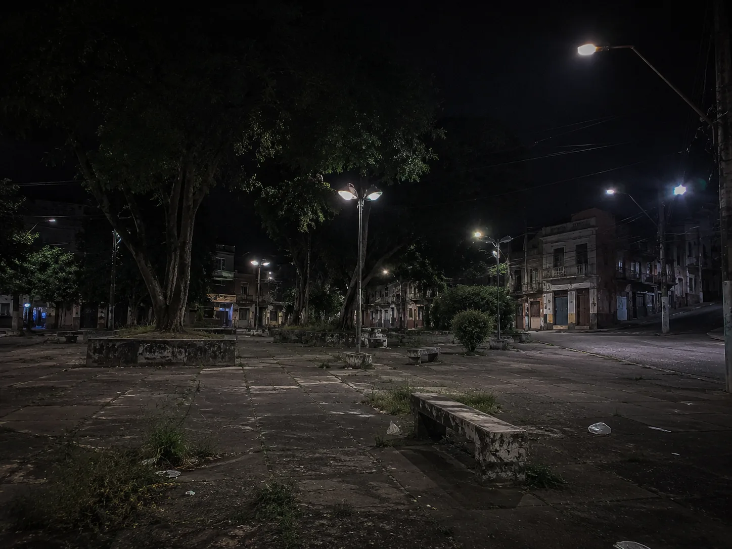 Largo arborizado vazio e escuro à noite, com aspecto inseguro