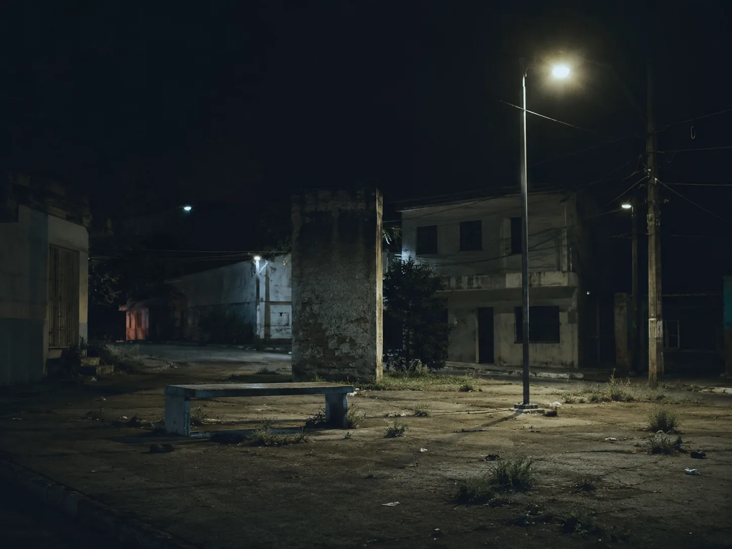 Praca pequena de bairro vazia e mal iluminada a noite, com aspecto inseguro