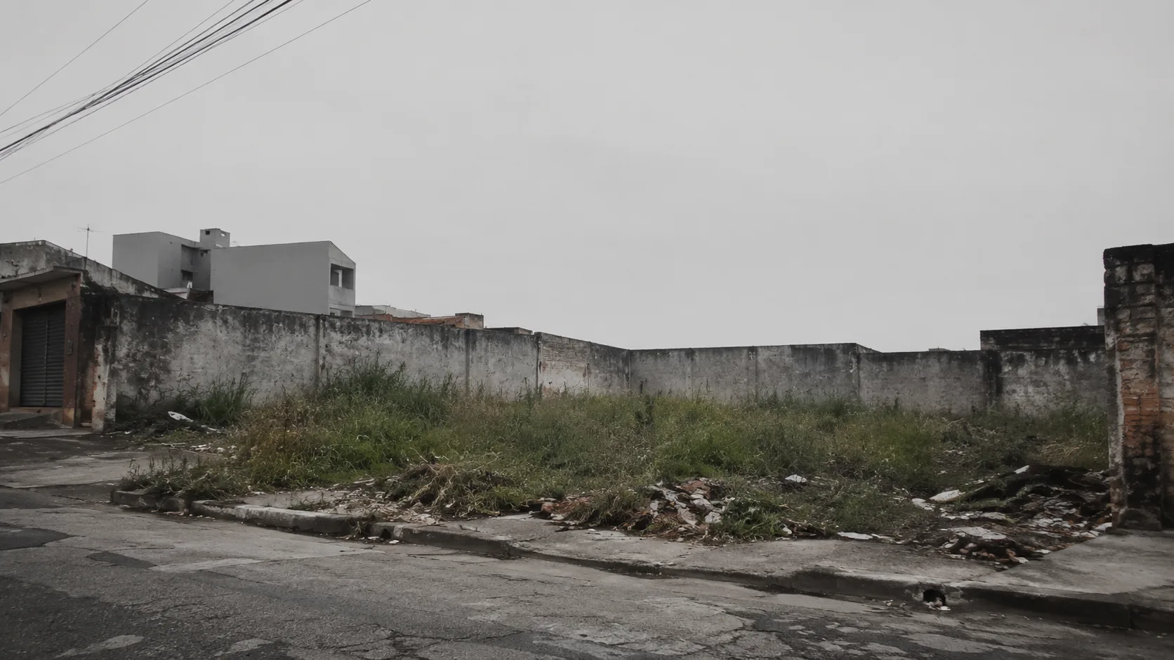 Terreno baldio murado em esquina de bairro, com mato e entulho na calçada, exemplo de ponto de vergonha em cidade do Sudeste do Brasil